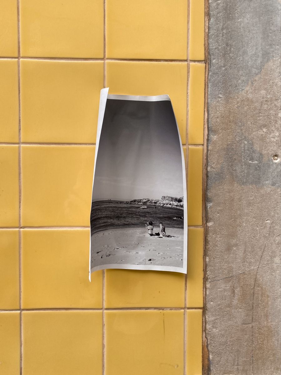 Schwarz-Weiß-Fotografie eines Strandes, an eine gelbe Fliesenwand geklebt